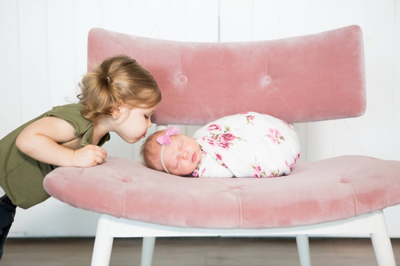 Big sister kissing her newborn sibling